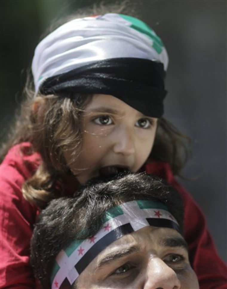 A Syrian wears a Syrian independence flag headband as he carries a young girl on his shoulders during anti-Syrian regime protest outside the Arab League headquarters in Cairo, Egypt, on Sunday. 